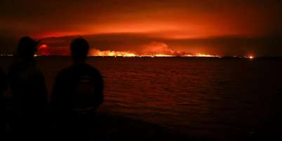 Turistas observam incêndio florestal atingir uma área de mata próxima à baía de Arcachon, no oeste da França, em meio ao agravamento da seca após uma onda de calor e à escassez de água em grande parte do país, em 24 de julho de 2026. Foto: REUTERS - Stephane Mahe / RFI