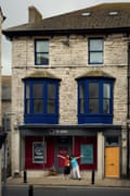 A woman and a man stand with their arms open wide in front of the bnb-side B&B