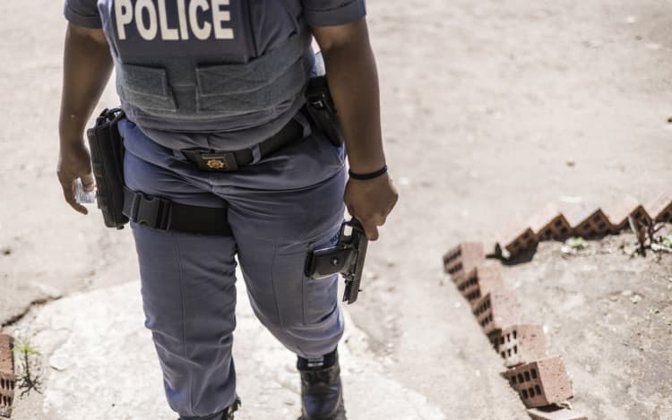 A South Africa Police Service (SAPS) officer holds a confiscated 9mm pistol at the Isulabasha Primary School at the Mistake Farm area in Umzinto, on November 1, 2021. Voters who opposed the candidate imposed by the ruling African National Congress (ANC) barricaded the road with large stones and dug a trench to prevent Electoral Commission officials to reach the voting station at the Isulabasha Primary school, de facto shutting down in protest the only voting station in the area. South African Po