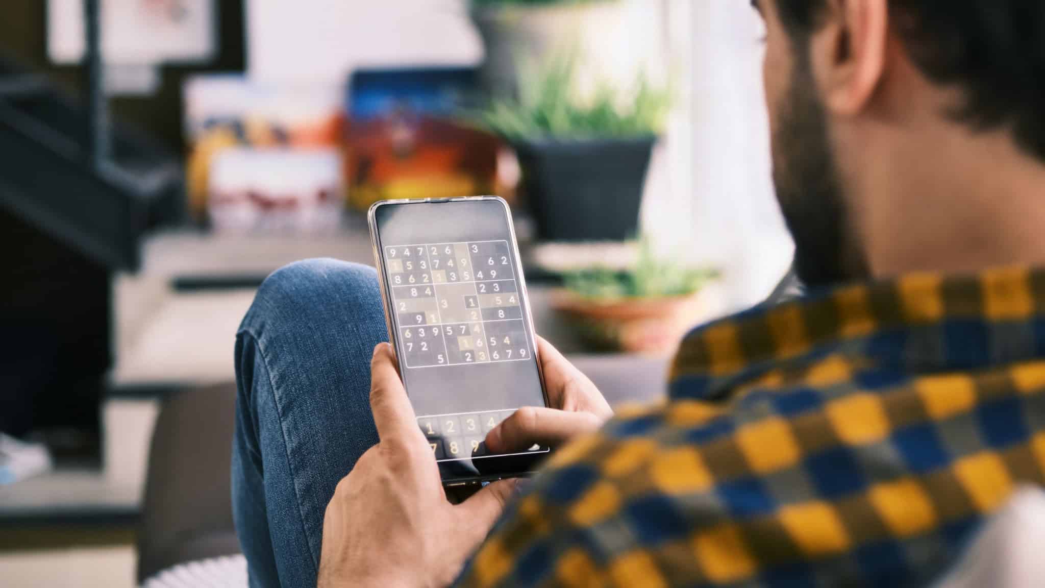 Homem jogando Sudoku no celular